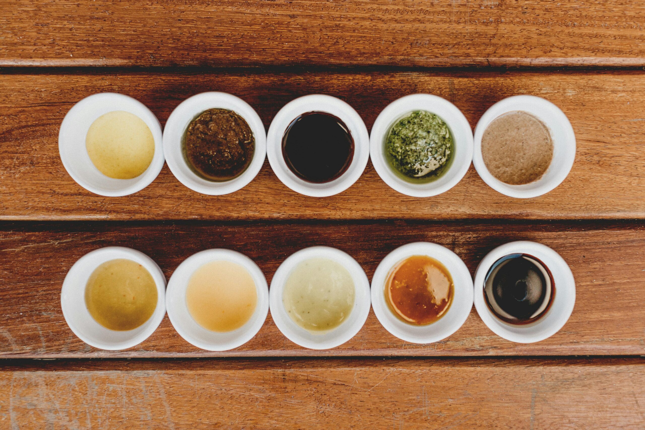 Assorted sauces displayed in bowls on a rustic wooden table.