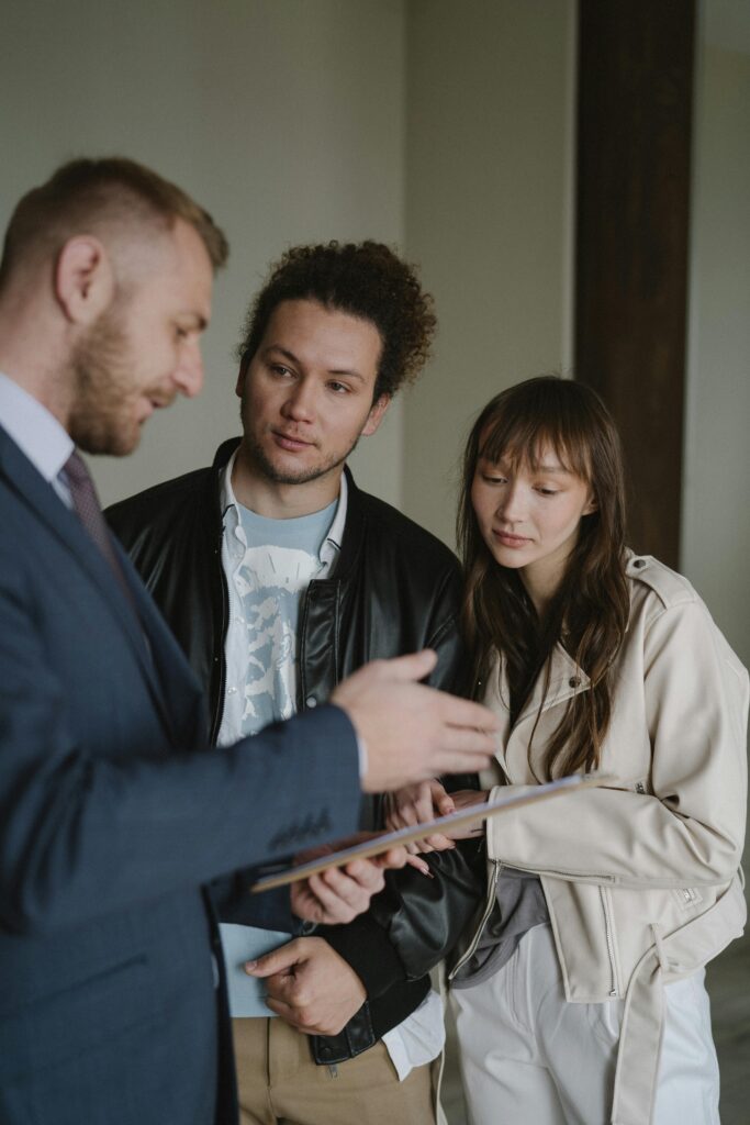 A real estate agent conversing with a potential client couple inside a modern home.